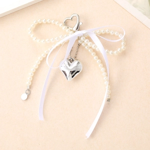 Détail d'un pendentif en perles avec ruban blanc et un cœur argenté élégant