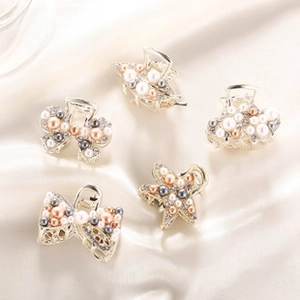 Close-up of five rhinestone bow and star mini hair claws on beige silk background