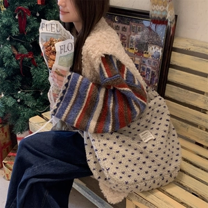 Detail of plush cream tote bag with blue polka dots shown in cozy indoor setting