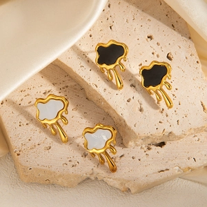 Close-up of irregular fluid earrings with gold frames in black and white enamel finishes