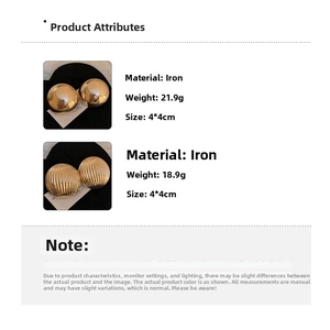 Detail view of round gold metallic stud earrings with smooth and ribbed textured finishes