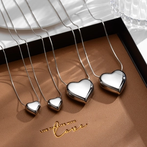 Polished silver heart pendant necklace set on brown leather tray in a lifestyle arrangement