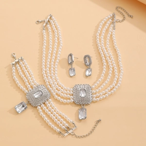 Détail à plat d'une parure de bijoux en perles et strass sur un fond beige neutre