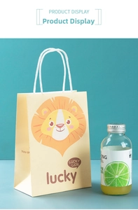 Detail of yellow paper gift bag featuring cute cartoon lion and sturdy white handles