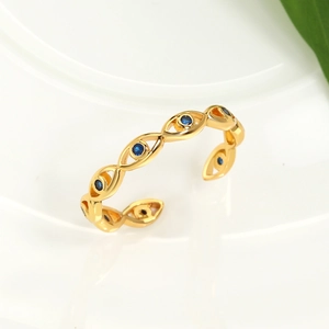 Macro detail of gold devil eye open ring with blue crystal insets on a white ceramic plate