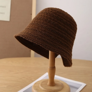 Close-up of caramel brown knitted bucket hat texture on a wooden stand