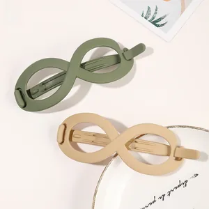 Close-up of infinity shaped matte hair clips in olive green and beige colors