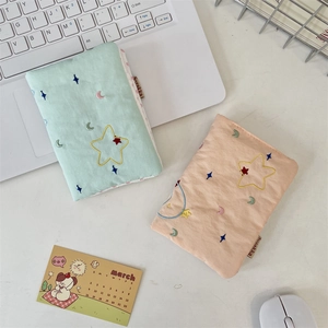 Detail of embroidered star patterns on mint green and peach fabric passport holders