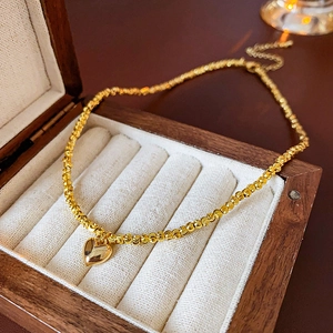 Macro shot of gold beaded necklace with heart pendant resting in a premium wooden jewelry box