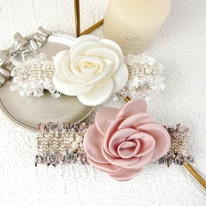 Detail of satin rose scrunchies with faux pearl accents on tweed base for hair