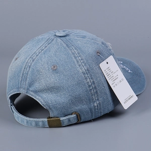 Dettaglio cappello da baseball in denim azzurro con fibbia metallica e ricamo bianco