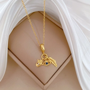 Detailed macro view of gold Hamsa hand, evil eye, and feather charms on a luxury necklace