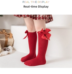 Détail de chaussettes festives rouges pour filles avec nœud en satin et bordure dorée