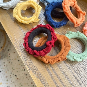 Detail shot of pleated knitted scrunchies in various solid colors on wooden edge