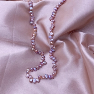 Close-up of purple baroque freshwater pearls on elegant pink silk satin fabric texture
