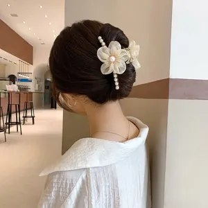 Detailed close-up of large floral hair claw clip with pearls and fabric petals on model