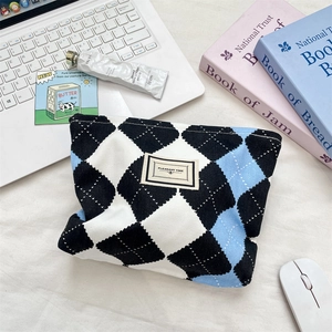 Flat lay of a checkered toiletry bag with PLEASANT TIME label among office desk accessories