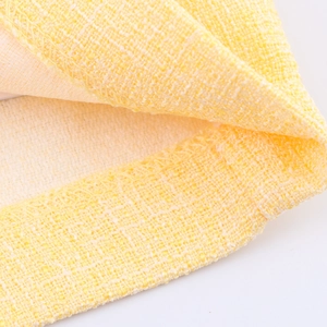 Primo piano del tessuto tweed giallo con cuciture overlock raffinate per set vestito