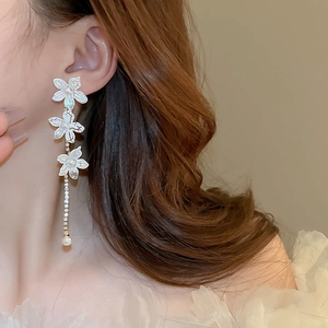 Detail of elegant white lily earrings with pearl tassels and shimmering crystal fringe