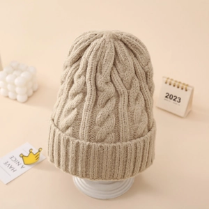 Close-up of beige cable-knit winter beanie showing thick knit texture and wide folded cuff