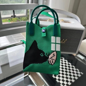 Détail du mini sac tricoté vert avec motif chat noir et fermeture à bouton bleu