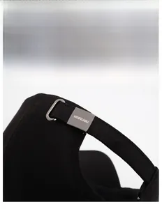 Gros plan sur la boucle métallique réglable et la texture du bonnet noir de baseball