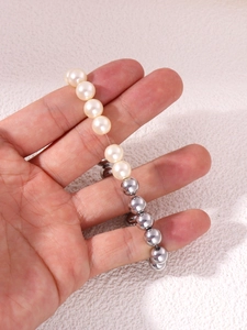 Dettaglio di perle d'acqua dolce e sfere argentate su un bracciale elastico flessibile