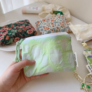 Détail d'un porte-monnaie en coton à imprimé floral avec fermeture éclair et étiquette