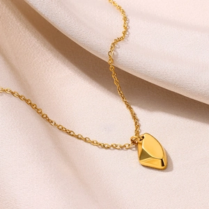 Gros plan d'un collier avec pendentif géométrique doré sur du velours de soie