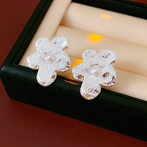 Detailed close-up of silver irregular flower earrings with pearl in a jewelry box