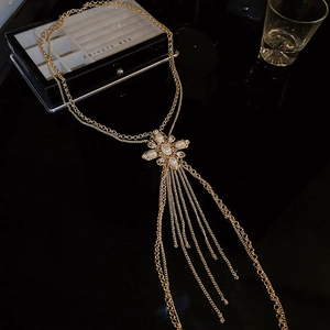 Detail of gold body chain with pearl star pendant and long tassel fringe overlay