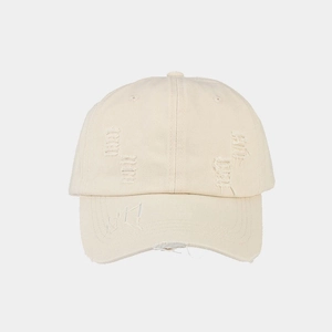 Detail of distressed beige baseball cap with frayed holes and blue abstract embroidery