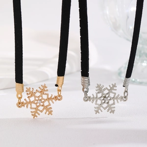 Macro shot of snowflake pendants in gold and silver finish with rhinestones on black velvet