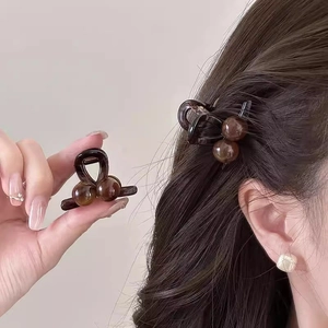 Close-up of translucent amber mini hair claw clip being worn as a side hair styling accessory