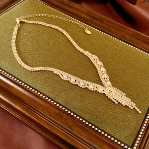 Detailed view of luxury gold tassel necklace with marquise zircons on green velvet