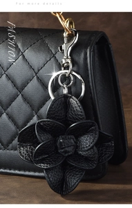 Close-up of black leather camellia flower keychain with silver metal lobster clasp