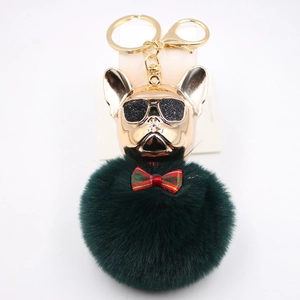 Dettaglio portachiavi bulldog francese con testa dorata, pompon verde e papillon