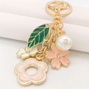 Detail of floral keychain with green enamel leaves, colorful flowers and pearl charm