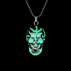 Close-up of hip hop skull necklace pendant with glowing green effect on black background