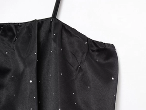 Détail du haut bustier noir orné de strass brillants et d'un tissu satiné lisse