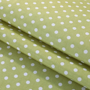 Close-up of grass green linen fabric with white polka dots showing textile texture
