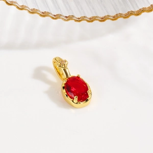 Detail showing an 18k gold plated turtle pendant with an oval red gemstone and floral bail
