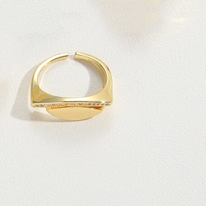 Macro shot of gold geometric ring with small inset zircons on textured white background