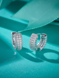 Macro shot of silver hoop earrings with pave-set cubic zirconia on blue ribbon