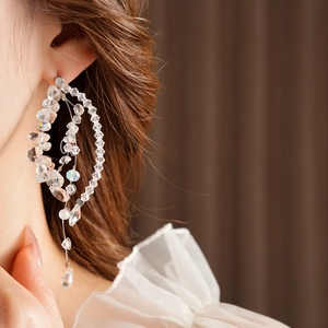 Macro shot of tiered transparent crystal beaded drop earrings on a model's ear
