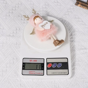 Detailed view of pink plush Christmas angel ornament weighing 11g on a scale