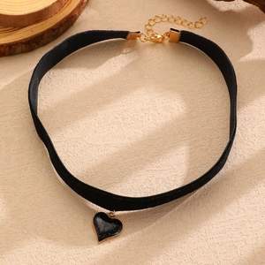 Dettaglio del choker in velluto nero con ciondolo a cuore e catena in metallo dorato