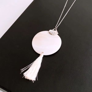 Detail of silver shell clasp and white mother-of-pearl pendant with tassel on black leather