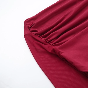 Detail of red off-shoulder top with mesh sleeve stitching and pleated fabric texture