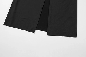 Detail view of the elegant hem side slit and neat stitching on a black long sleeve dress